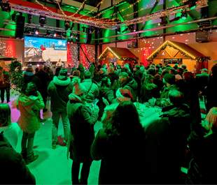 Indoor-Weihnachtsmarkt auf dem EUREF-Campus Berlin Indoor-Weihnachtsmarkt mit Gästen, weihnachtlichen Hütten und gemütlicher Dekoration