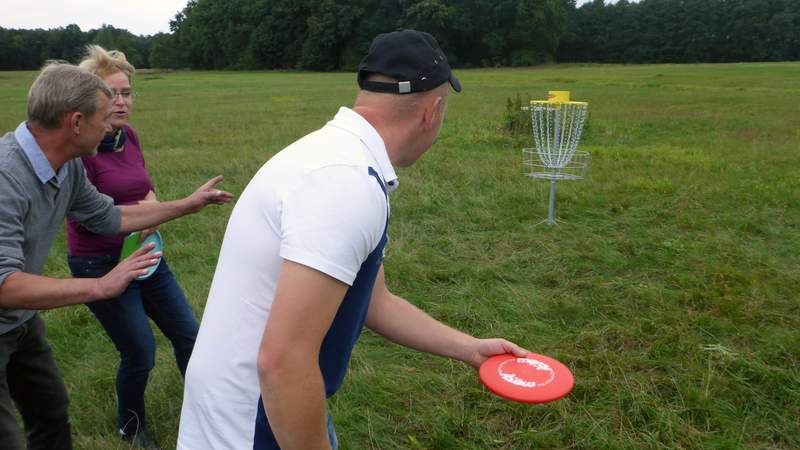 Drei Kollegen spielen Disc Golf