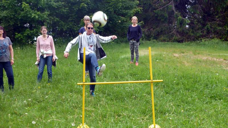 Frau schießt Ball über eine Hürde beim Fun Golf Teil Fußball-Golf