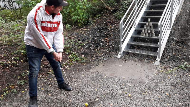 Ein Mann spielt Crossgolf neben einer Treppe