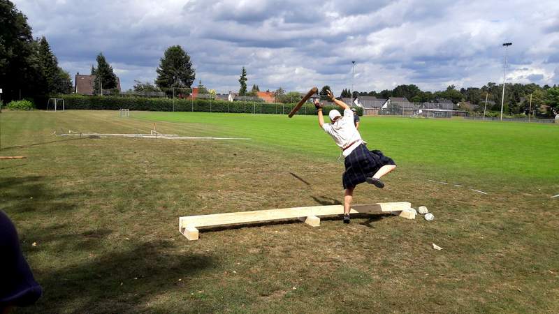 Highland-Games auf Schloss Dennenlohe als Firmenfeier Ein Mann wirft einen Baumstamm