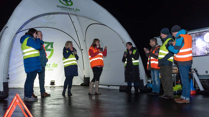 Gruppe von Menschen mit Warnweste essen im Stehen