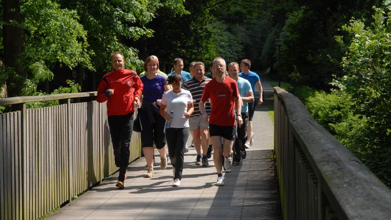 Kai Röckert joggt mit den Gästen über eine breite Brücke.