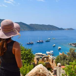 Dame mit Hut schaut auf das türkische Meer mit Booten