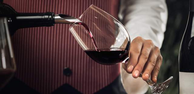 Ein Mann schenkt Wein in ein Glas