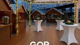 Weihnachtlich geschmücktes Zelt mit Stehtischen und Weihnachtsmarkthütten und dem Schriftzug "GOP Weihnachtsmarkt".