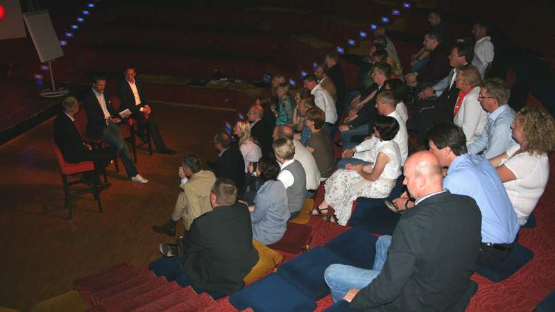 Gästen sitzen im Auditorium und auf der Bühne sitzen drei Talkrunden-Sportler