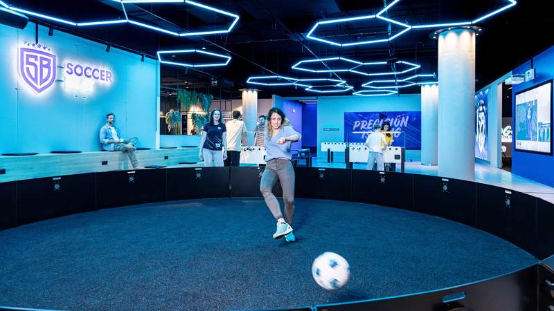 Eine Frau spielt einen Fußball gegen eine Bande