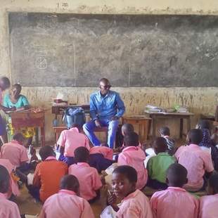 In einem Klassenraum in Kenia sitzen alle Kinder am Boden, einen Tisch gibt es nur für die Lehrperson