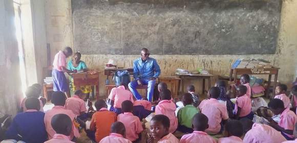 In einem Klassenraum in Kenia sitzen alle Kinder am Boden, einen Tisch gibt es nur für die Lehrperson