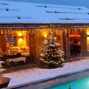 Dachterrasse im Winter mit beleuchteter Hütte Verschneite Dachterrasse des Chalet O am Abend mit beleuchteter Alpenhütte, Tannen und Pool