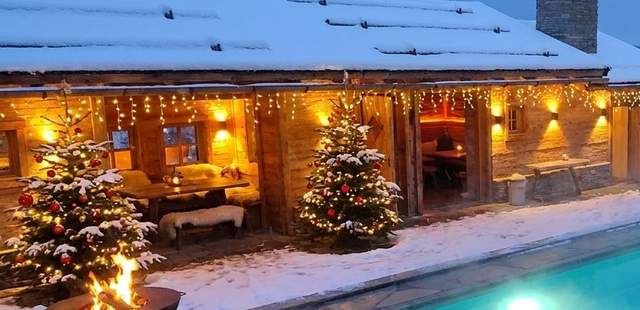 Dachterrasse im Winter mit beleuchteter Hütte Verschneite Dachterrasse des Chalet O am Abend mit beleuchteter Alpenhütte, Tannen und Pool