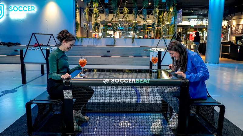 2 Frauen spielen Fußball in einer kleinen Box mit zwei Toren