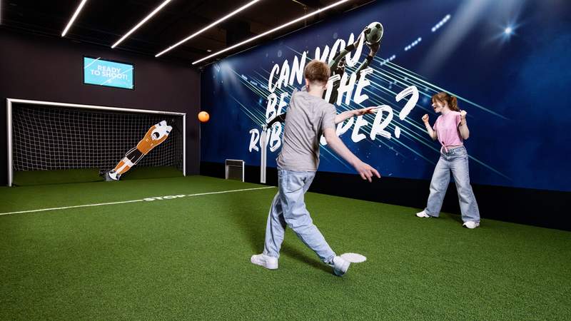 Junge schießt mit orangenen Ball auf den RoboKeeper