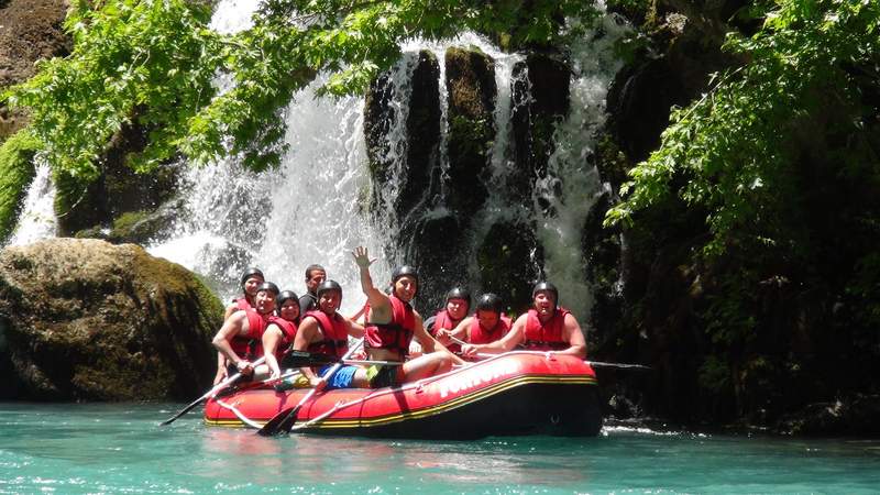 Rotes Raftingboot mit lachenden Menschen auf dem Wasser