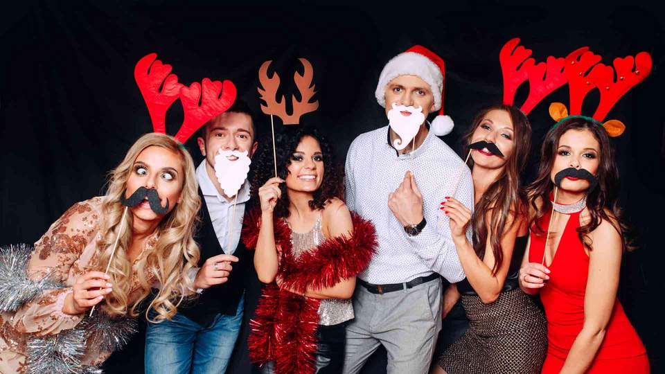 Weihnachtsfeier im Team Menschen, die sich eine Weihnachtsmaske vor das Gesicht halten