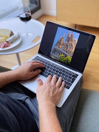 Der Gast sitzt auf einem Sofa mit seinem Laptop.