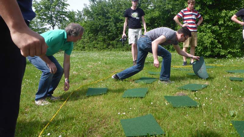 Spieler spielen Teambuildingaktion Geheimer Code mit Filzplatten im Kreis