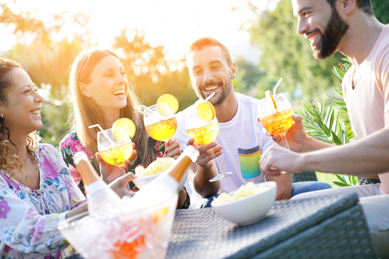 Menschen an einem Stehtisch mit Cocktails in der Hand