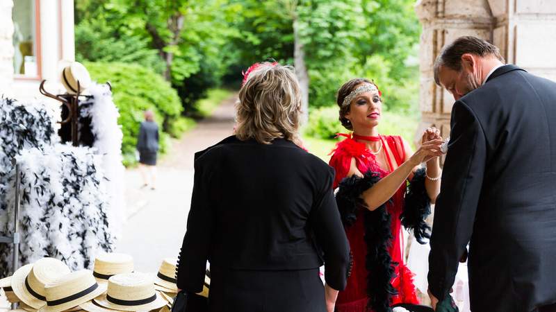 Eine Dame im 20er Jahre Look verteilt Hüte und Accessoires