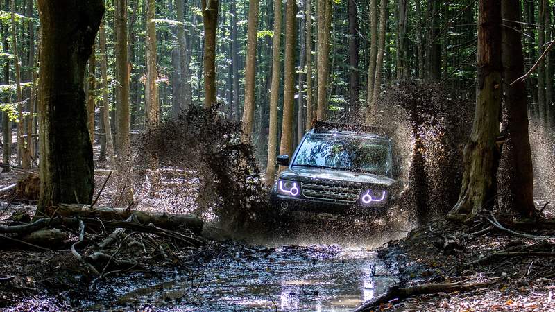 Landrover fährt durch einen Schlammweg im Wald