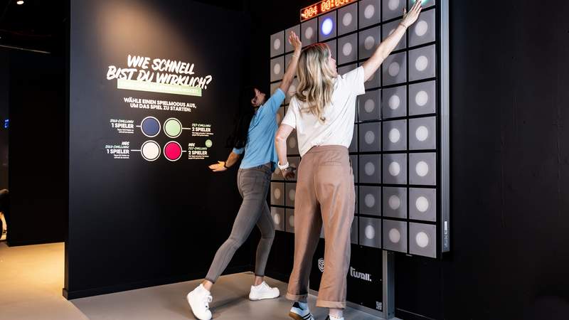 2 Personen spielen gegeneinander an einer Reaktionswand