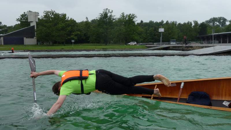 Ein Kanufahrer springt samt Paddel aus dem Kanu ins Wasser.