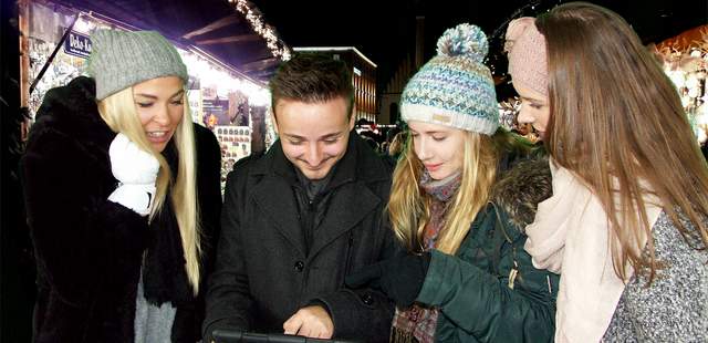 Ein paar Menschen spielen eine City Rallye auf dem Weihnachtsmarkt