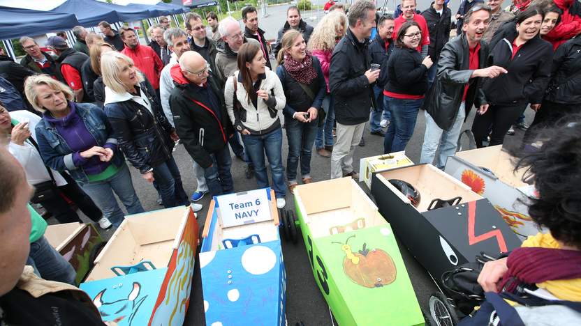 Menschen stehen hinter bunt bemalten Seifenkisten
