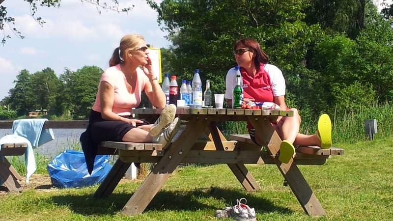 Gunda Niemann-Stirnemann und Birgit Fischer sitzen auf einer Holzbank und unterhalten sich