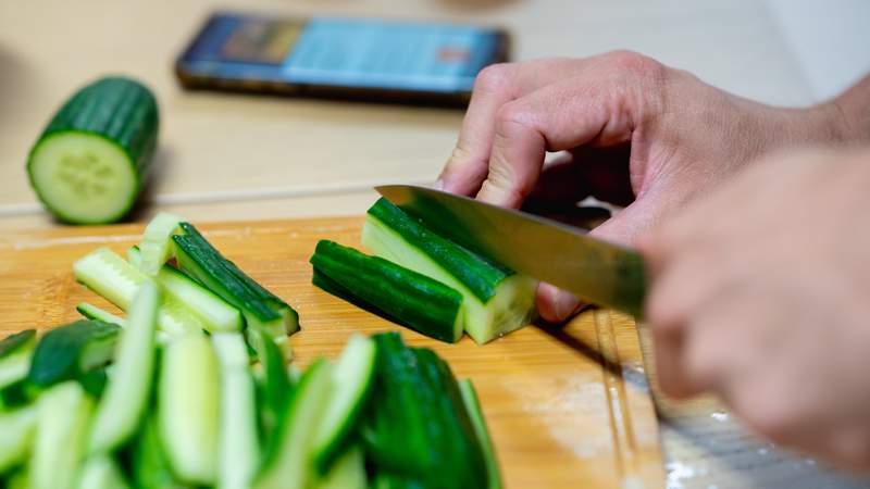 Teilnehmer schneidet frische Gurken während eines interaktiven Kochworkshops von Mundet-App