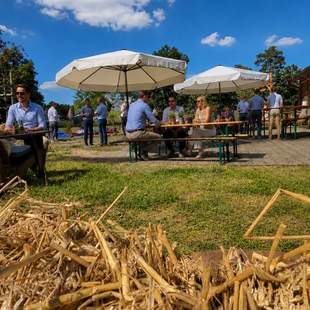 Pop-up Westernfest mit Heuballen, Sitzbereichen, Sonnenschirmen und Gästen auf dem Veranstaltungsgelände