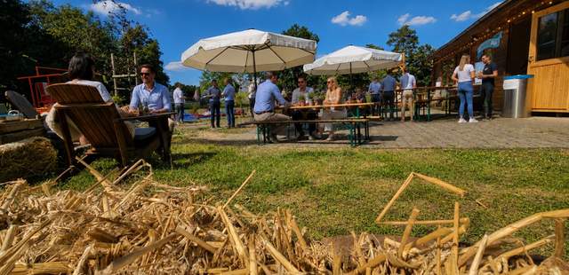 Westernfest mit rustikaler Eventfläche Pop-up Westernfest mit Heuballen, Sitzbereichen, Sonnenschirmen und Gästen auf dem Veranstaltungsgelände