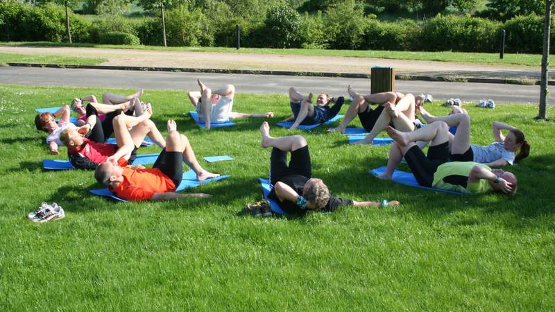 Sportliche menschen liegen im Gras und macht Gymnastik