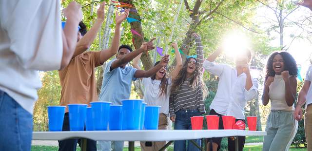 Eine Gruppe von Freunden spielt zusammen Bier-Pong in einer festlichen Gartenlocation
